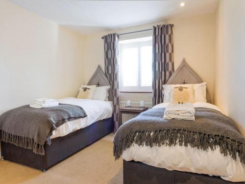 1 dormitorio con 2 camas y ventana en The Gatehouse Cottage, en Wells