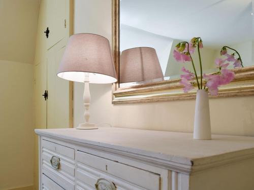 a table with a lamp and a vase with flowers on it at Dulcie Cottage in Benson