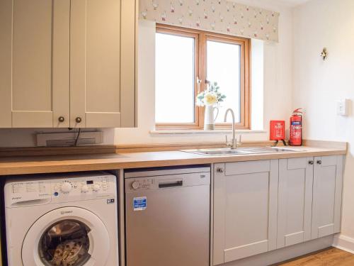 een keuken met een wasmachine en een wastafel bij The Larches in Hopton Cangeford