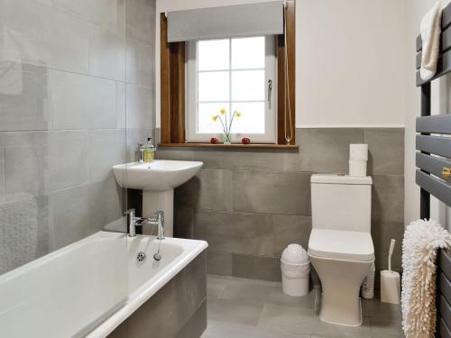 a bathroom with a tub and a sink and a toilet at Baldowrie Farm Cottage in Ardler