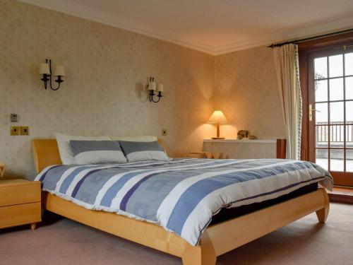 um quarto com uma cama grande com lençóis azuis e brancos em Stronafian House em Feorlean