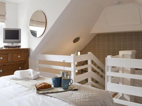 Un dormitorio con una cama con una bandeja de comida. en Horseshoe Cottage, en Fife