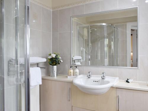 a white bathroom with a sink and a mirror at Horseshoe Cottage in Fife