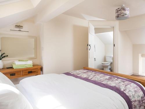 a white bedroom with a bed and a bathroom at Willow Cottage At Naze Farm-uk32760 in Chinley