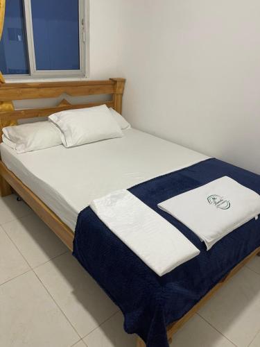 a bed with a blue and white blanket on it at Bambú Cabaña Campestre in Turbo
