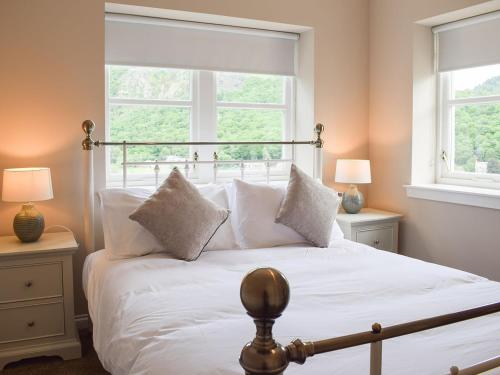 a bedroom with a white bed with two windows at Forth View-uk34217 in Aberfoyle