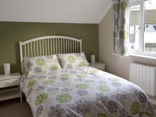 a bedroom with a bed with a floral bedspread and a window at Lake View in Bowness-on-Windermere
