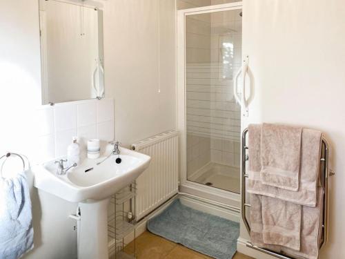 a white bathroom with a sink and a shower at Rose Cottage in Blakemere
