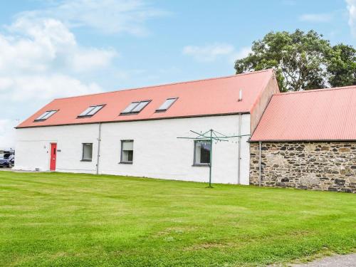a white barn with a red roof and a grass field at The Stable - Uk33400 in Isle of Gigha