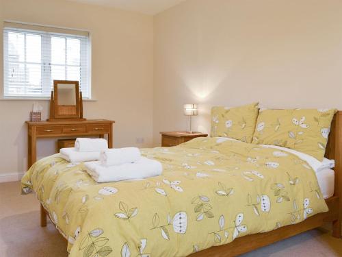 a bedroom with a bed with a yellow comforter at Croft Cottage 2 - Uk10588 in Stillington