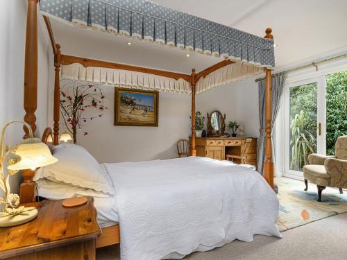 1 dormitorio con cama con dosel y mesa en Treetops, en Fairbourne