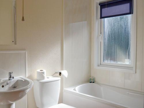 a bathroom with a sink and a toilet and a bath tub at Lodge A- Uk33088 in Dinnet