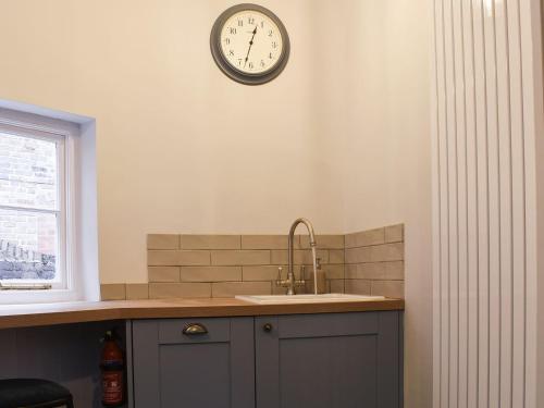 a kitchen with a sink and a clock on the wall at Dusty House in Ashbourne