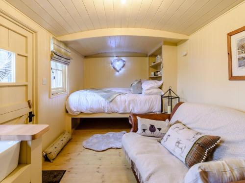 um pequeno quarto com 2 camas e um sofá em The Lambing Shed em Ryhill