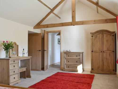1 dormitorio con alfombra roja y armario de madera en Grange Cottage en Nawton