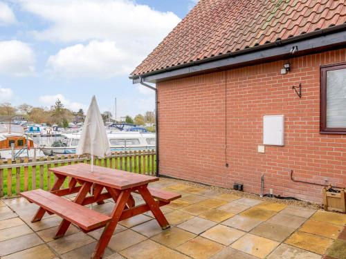 a wooden picnic table and an umbrella on a patio at Riverside Cottage in Loddon