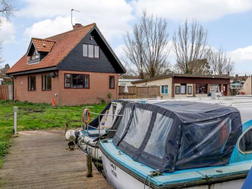 a boat parked on a dock in front of a house at Riverside Cottage in Loddon