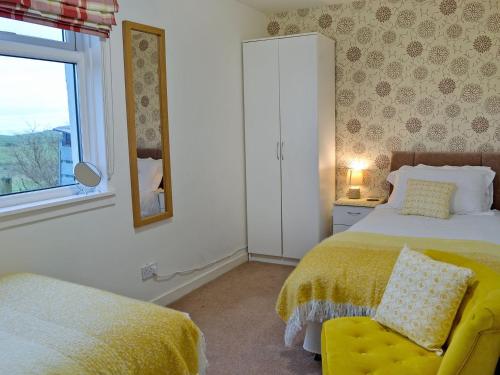 um quarto com uma cama, uma cadeira e uma janela em Kirklauchline Cottage em Portpatrick
