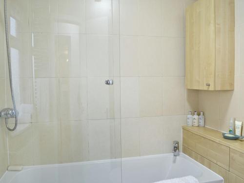 uma casa de banho com um chuveiro e uma banheira branca em Kirklauchline Cottage em Portpatrick