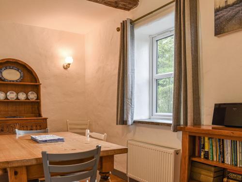 a dining room with a table and a window at Elderberry Cottage in Carnbrea