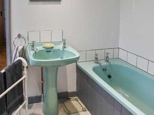 uma casa de banho com um lavatório verde e uma banheira em Elderberry Cottage em Carnbrea