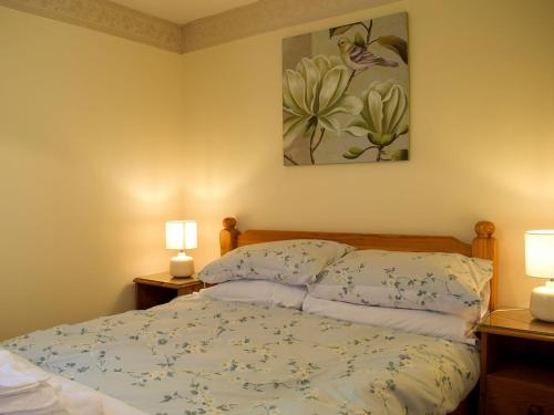 The Byre في Lympsham: غرفة نوم بسرير مع مصباحين ولوحة