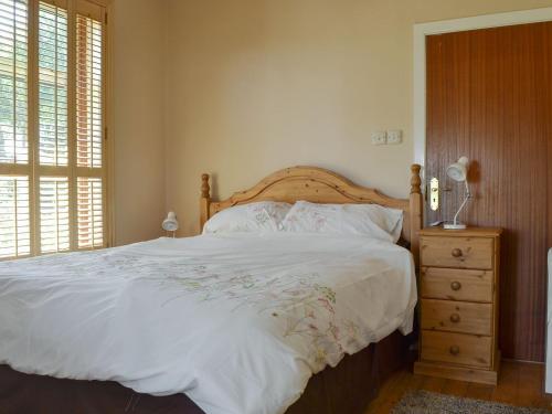 a bedroom with a large white bed with a wooden headboard at Borran Annexe in Colton