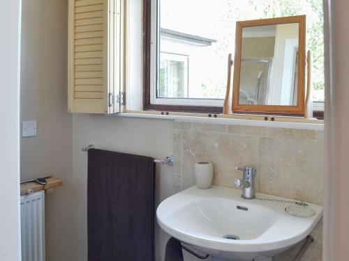 a bathroom with a sink and a mirror and a window at Borran Annexe in Colton