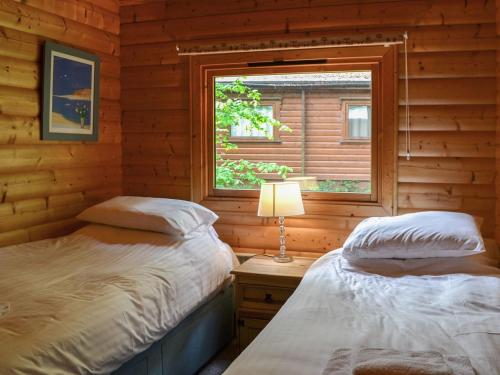2 camas en una cabaña de madera con ventana en Red Kite Lodge - Uk37417 en Legbourne