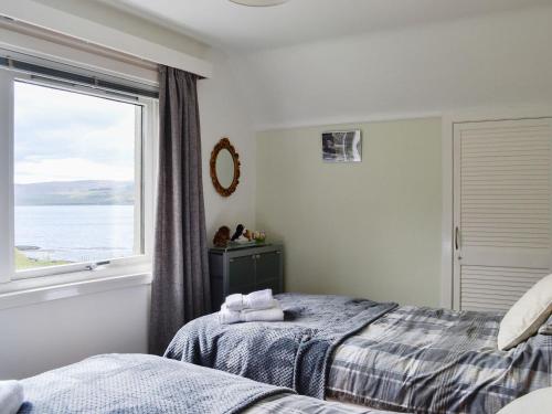 a bedroom with two beds and a window at Seaview Cottage in Bonnavoulin