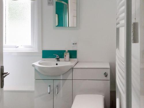 a white bathroom with a sink and a mirror at Seaview Cottage in Bonnavoulin