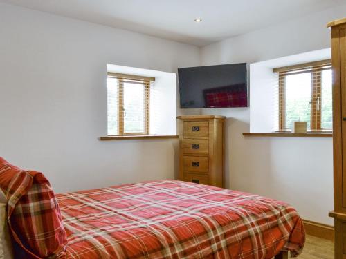 a bedroom with a bed and a dresser and windows at The Byres Tethera in St Bees