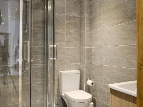 a bathroom with a toilet and a glass shower at The Byres Tethera in St Bees