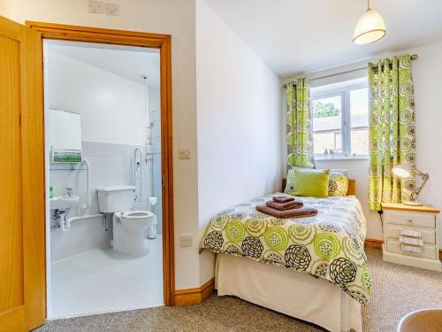 a bedroom with a bed and a shower and a toilet at The Woodlands Farmhouse in Threapwood