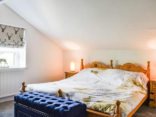 een slaapkamer met een houten bed met een blauwe poef bij Chapel Cottage in Robin Hood's Bay