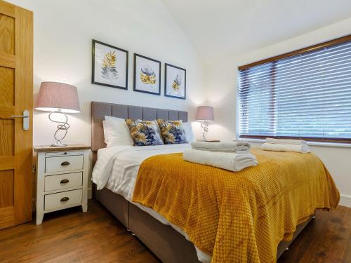 a bedroom with a bed with two lamps and a window at Little Orchard in Worlington