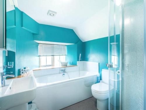 een blauwe badkamer met een bad, een toilet en een wastafel bij Well Farmhouse - Uk11880 in North Tamerton