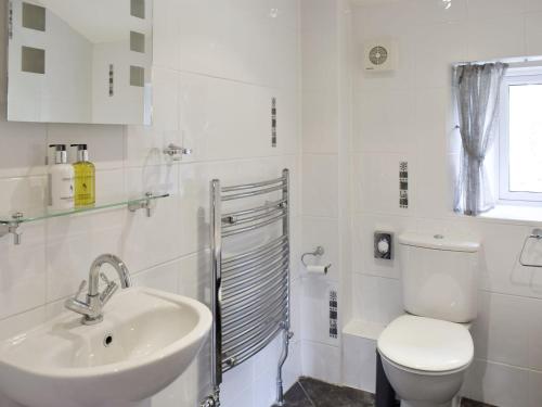 a white bathroom with a toilet and a sink at Thorneymire Cottage in Appersett