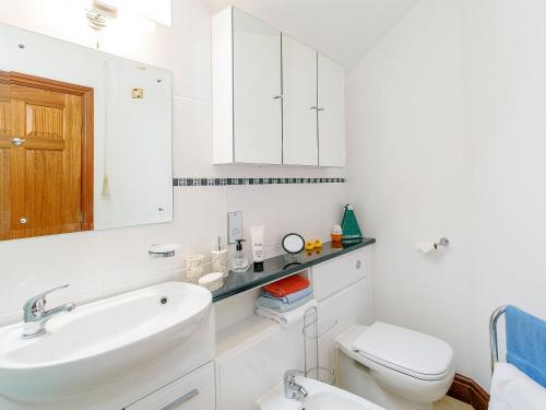 een witte badkamer met een wastafel en een toilet bij The Gatehouse-uk11836 in Dronfield