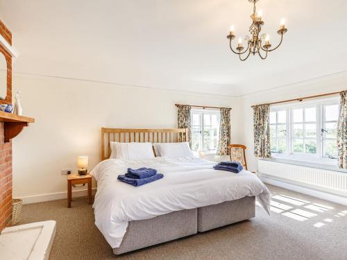 a bedroom with a large white bed with a chandelier at Mark Farmhouse in Bradwell on Sea
