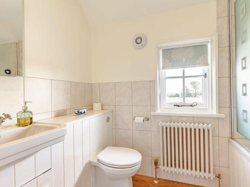 a bathroom with a toilet and a sink and a window at Mark Farmhouse in Bradwell on Sea