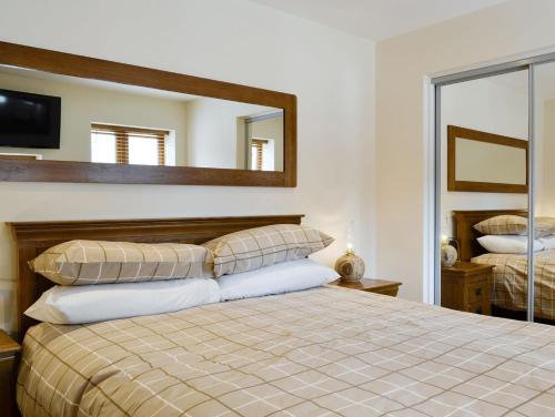 a bedroom with a large bed and a mirror at The Byres Tan in St Bees