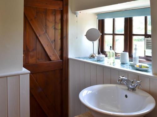a bathroom with a sink and a mirror and a window at Kates Cottage in Slingsby