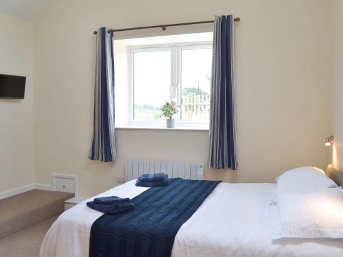 a bedroom with a bed and a window with blue curtains at Scrumpy Barn - Uk12014 in Luton