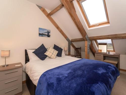 - une chambre avec un grand lit et une couverture bleue dans l'établissement Y Beudy, à Efenechtyd