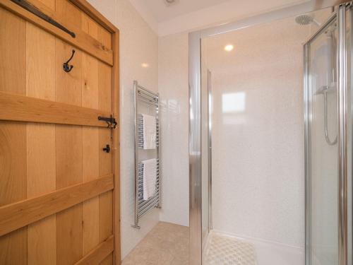 a bathroom with a shower and a glass door at Y Beudy in Efenechtyd