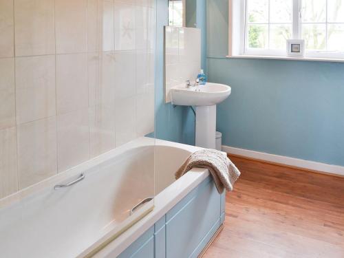 a bathroom with a bath tub and a sink at Highbury Farm Cottage in Wharram le Street