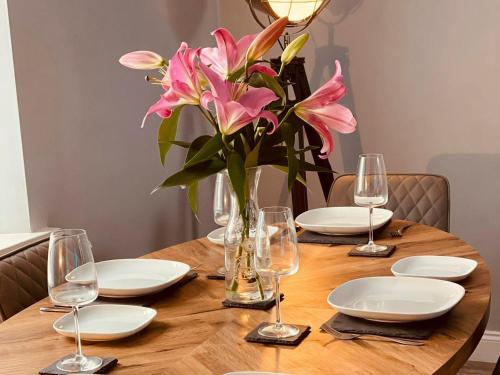 a table with plates and glasses and a vase with pink flowers at Ballypride in Girvan