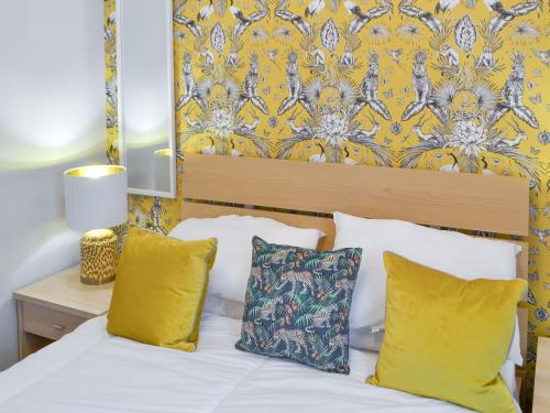 a bedroom with a white bed with yellow pillows at Percy Park Apartment in Tynemouth