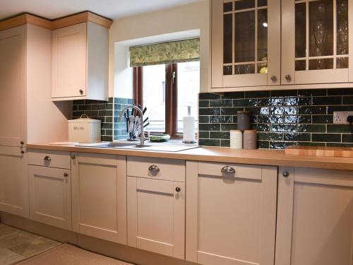 a kitchen with white cabinets and a sink at Primrose Bank in Tirril